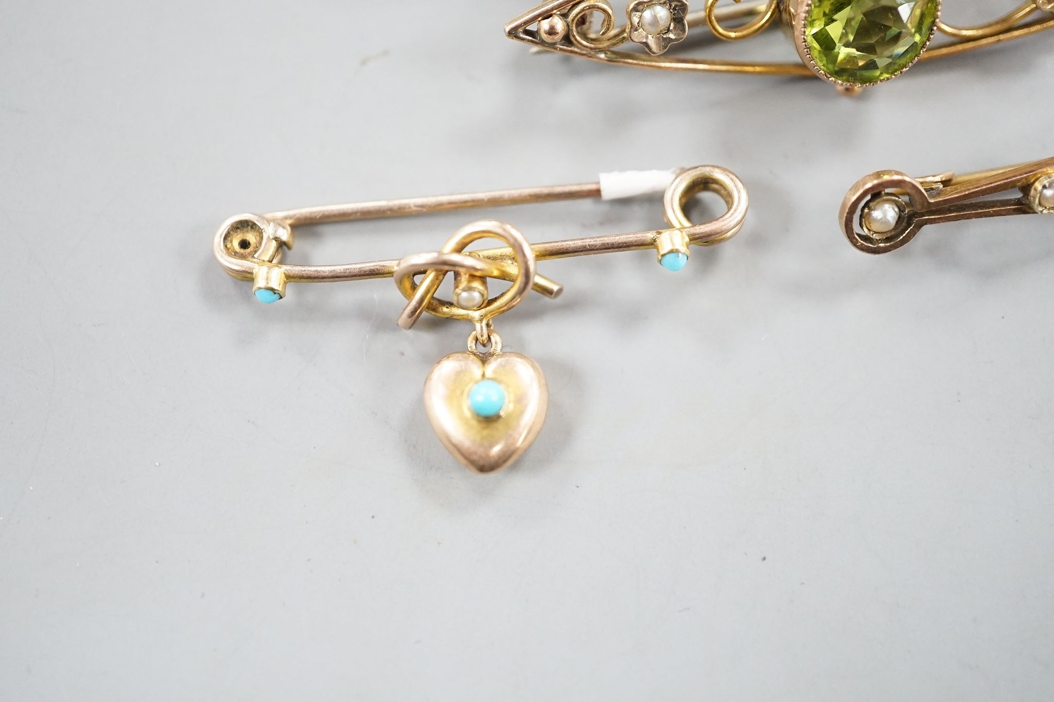 Five assorted early 20th century yellow metal and gem set brooches, including one 9ct and one with turquoise set heart drop and one with peridot, largest 62mm, gross 11.7 grams.